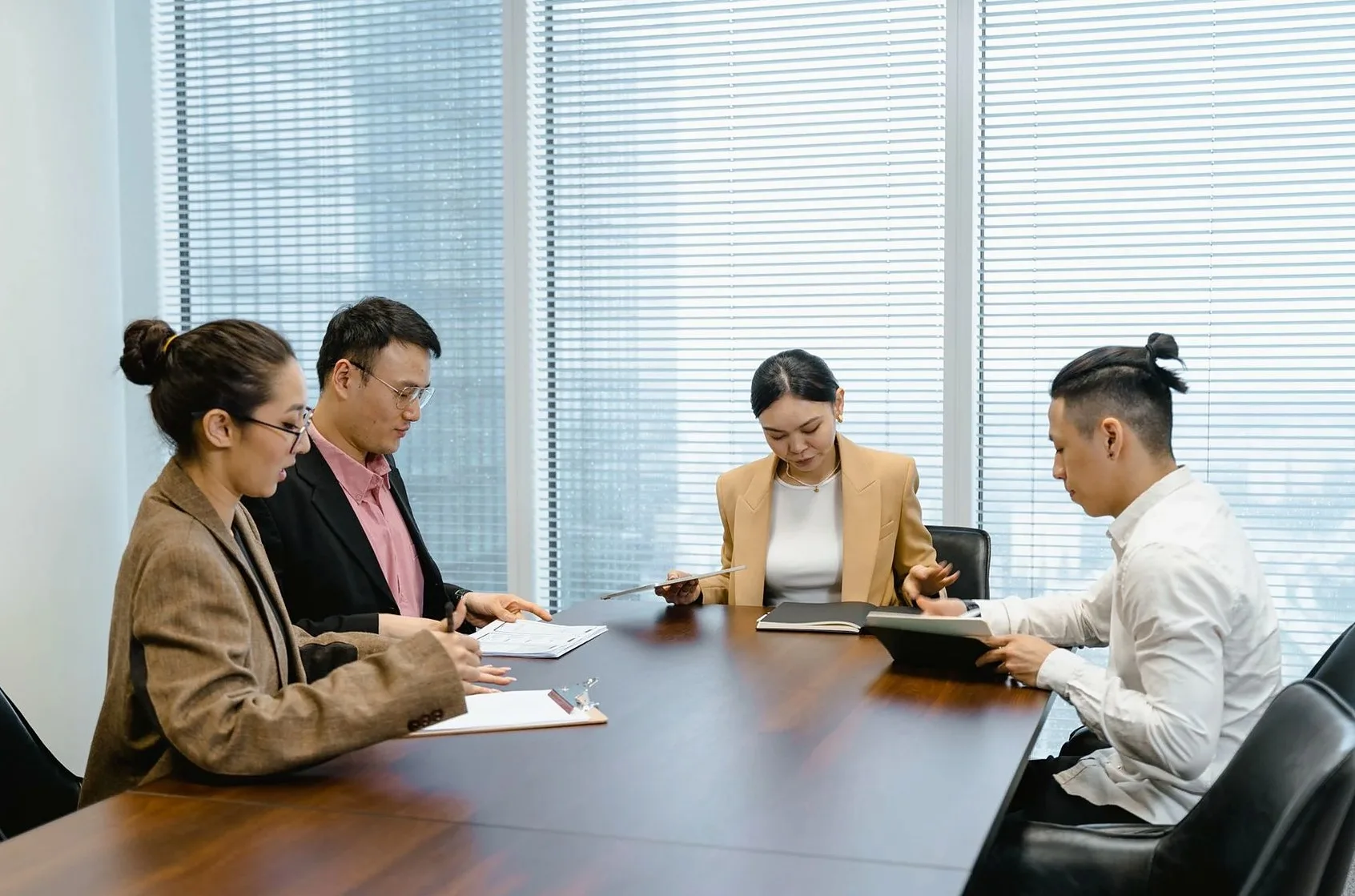 会議室のテーブルを囲んで打ち合わせをする4人